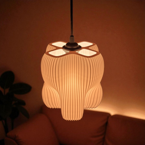 A pendant lamp with a sculptural design featuring four lobes and a finely striated surface is illuminated, casting a warm glow in a cozy setting. The soft light enhances the organic shape, creating an inviting atmosphere.