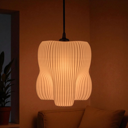 A stylish pendant lamp with an organic shape featuring four lobes, showcasing a finely striated surface that softly diffuses light. The warm glow creates an inviting atmosphere in a cozy interior setting, complemented by a nearby plant.