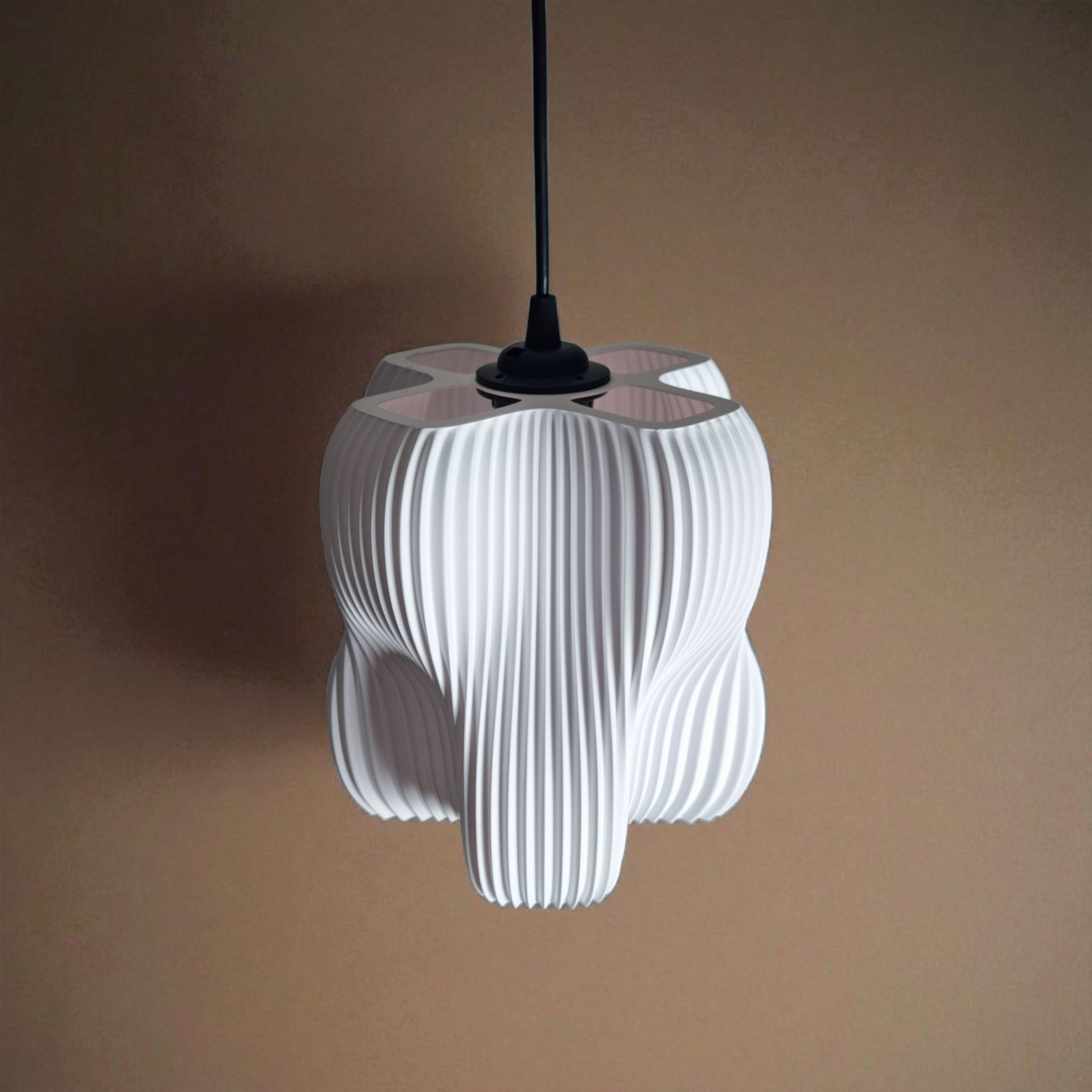 A white pendant lamp with a sculptural design featuring four lobes and finely striated surface details hangs against a warm, neutral background. The lamps unique shape and texture create an elegant focal point in the space.