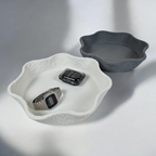 A decorative vide-poche set featuring two organically shaped bowls, one white and one gray. The white bowl has a textured, irregular edge, while the gray bowl is smooth, each holding a silver watch and a black smartwatch.