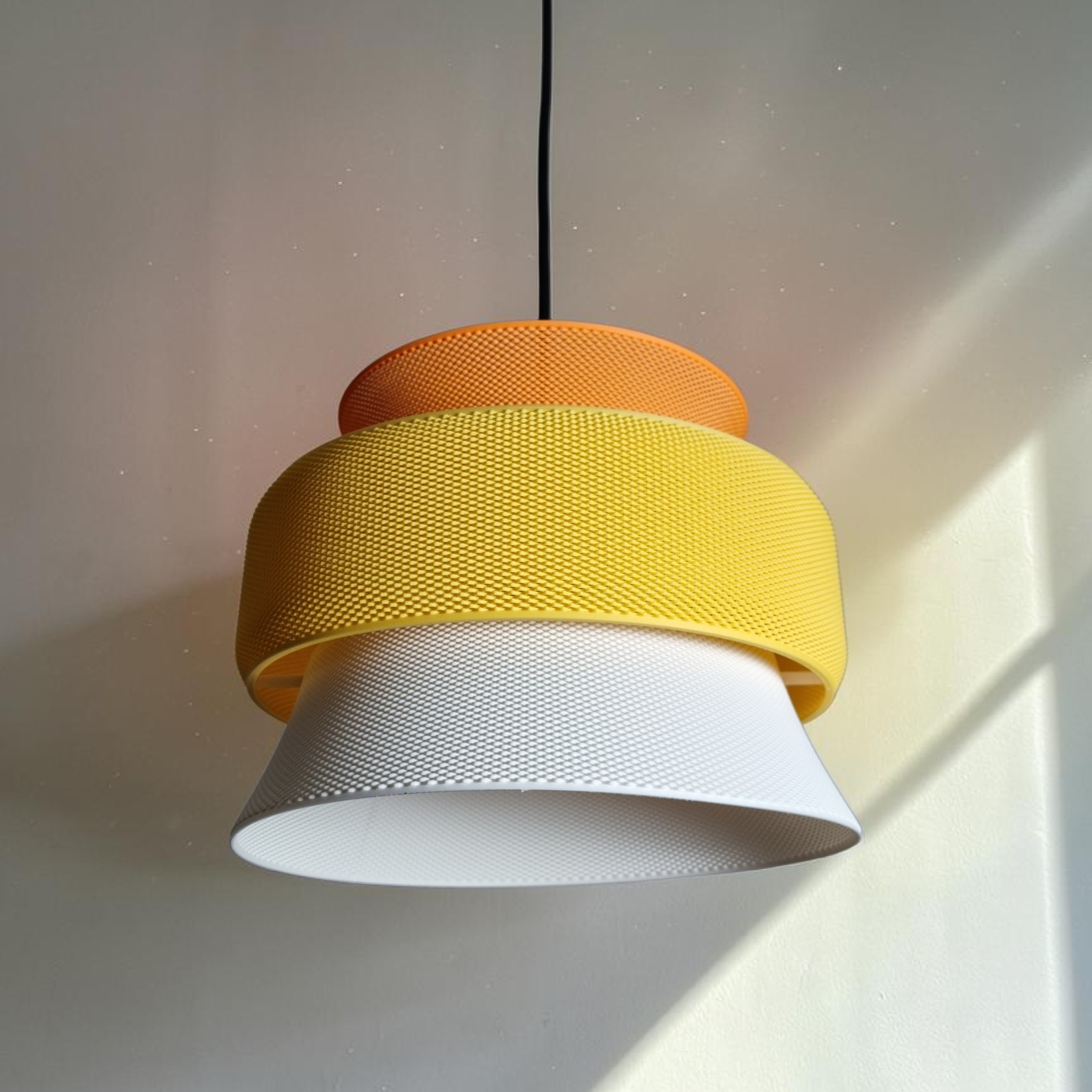 SAN pendant lampshade in plant-based bioplastic, three-tier orange yellow and white design, side view in natural light