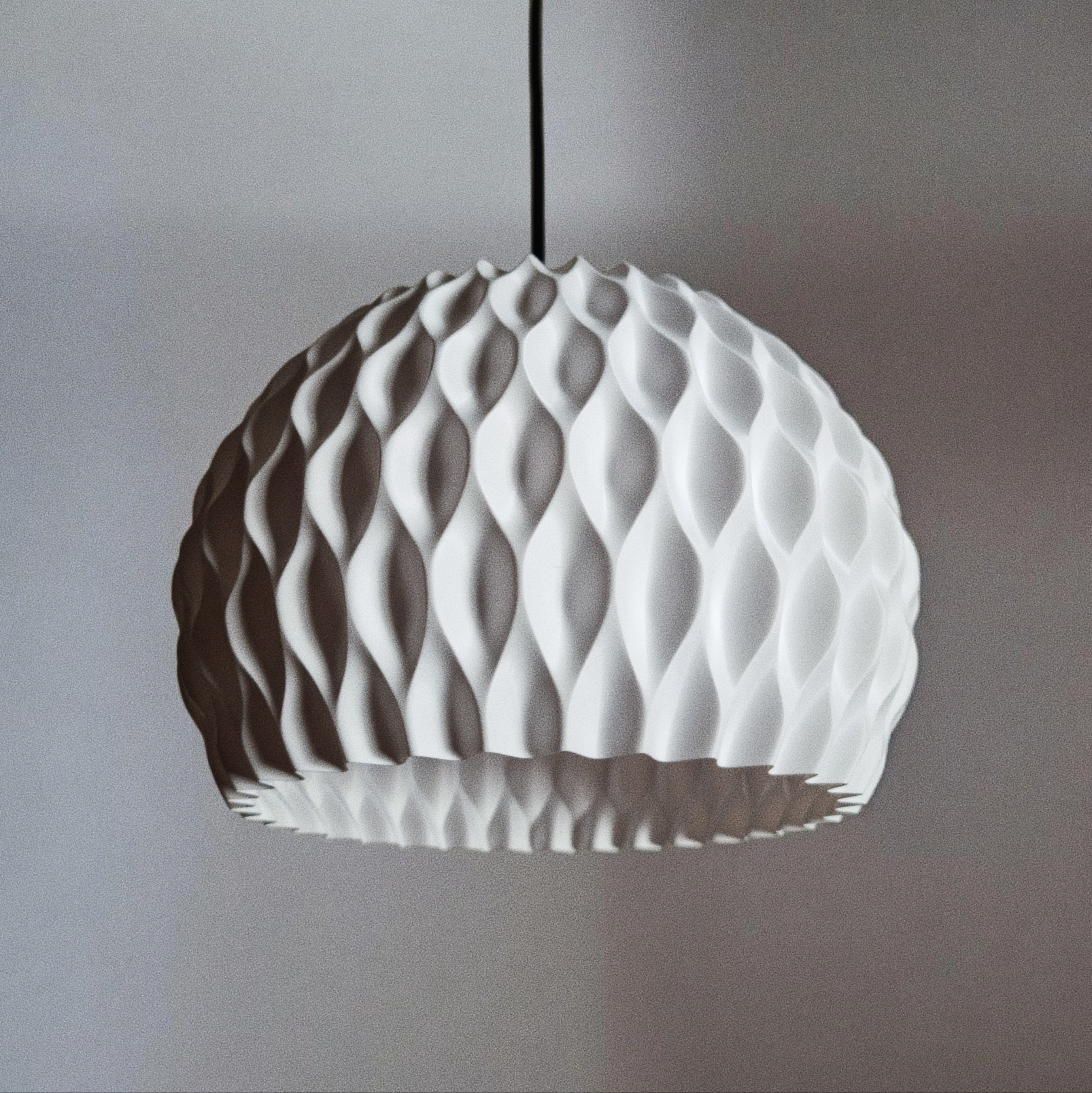 Gros plan de l'abat-jour WAVY blanc éteint sur fond gris, détail du motif en losanges ondulés