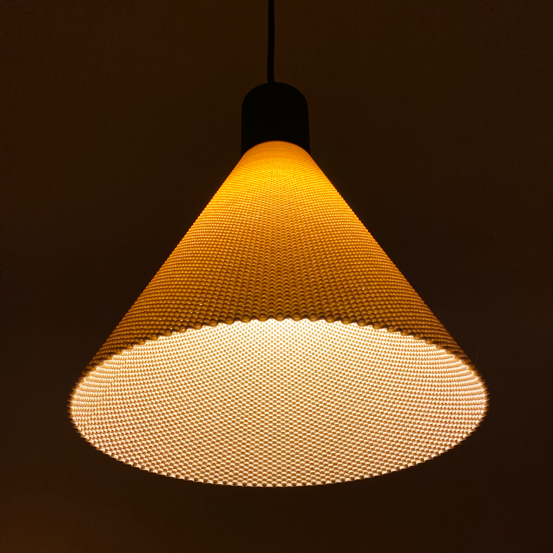 A conical pendant lamp hangs from the ceiling, featuring a textured surface that diffuses a warm, soft light. The lamps sleek design and golden hue create a modern, inviting atmosphere in the space.