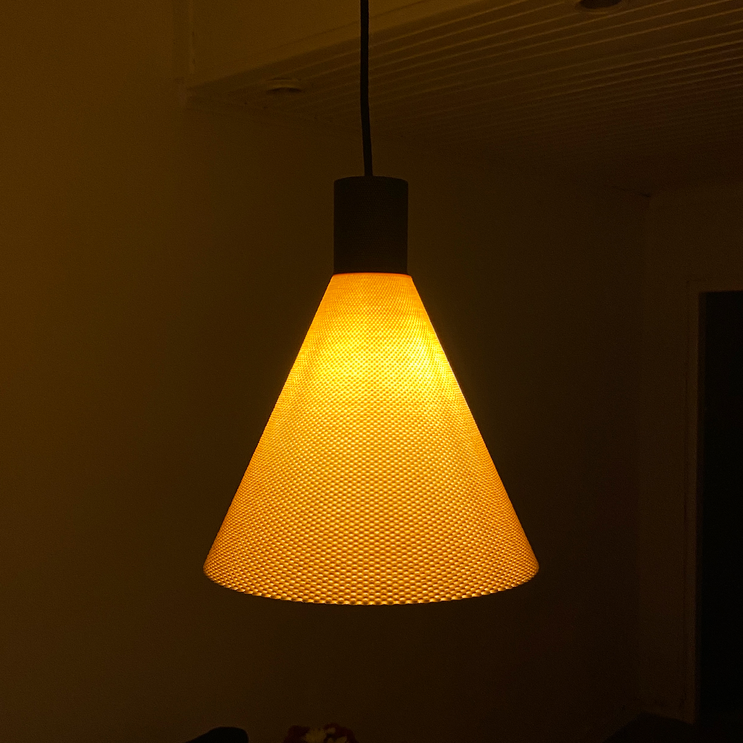 A warm, orange-hued pendant lamp with a conical shape and a textured surface hangs from the ceiling. The lamp casts a soft glow, creating a cozy atmosphere in the dimly lit room.