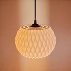 Abat-jour WAVY allumé sur fond sombre, lumière chaude révélant la profondeur du motif ondulé