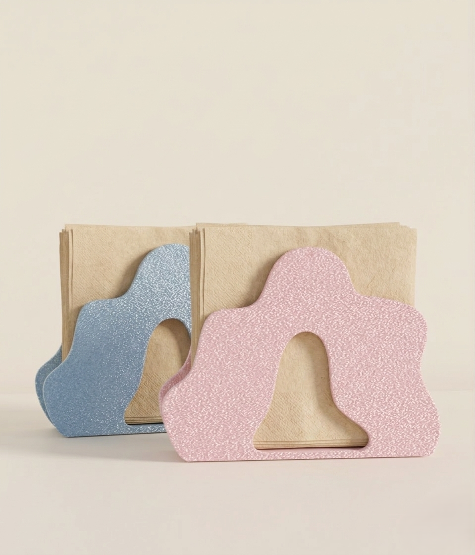 Two colorful napkin holders are displayed side by side, one in a soft blue shade and the other in a pastel pink.