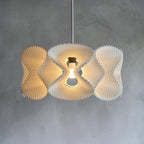 Abat-jour suspension COROA blanc, vue de face sur fond béton, texture perlée, ampoule LED E27, luminaire minimaliste Quarks