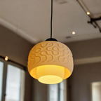 SEAMLESS designer pendant lamp illuminated over a modern interior, diffused warm light through the textured bioplastic shade