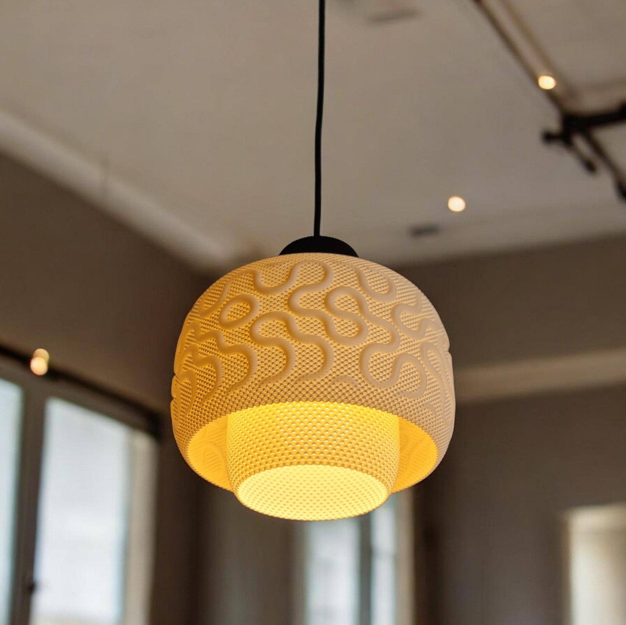 SEAMLESS designer pendant lamp illuminated over a modern interior, diffused warm light through the textured bioplastic shade