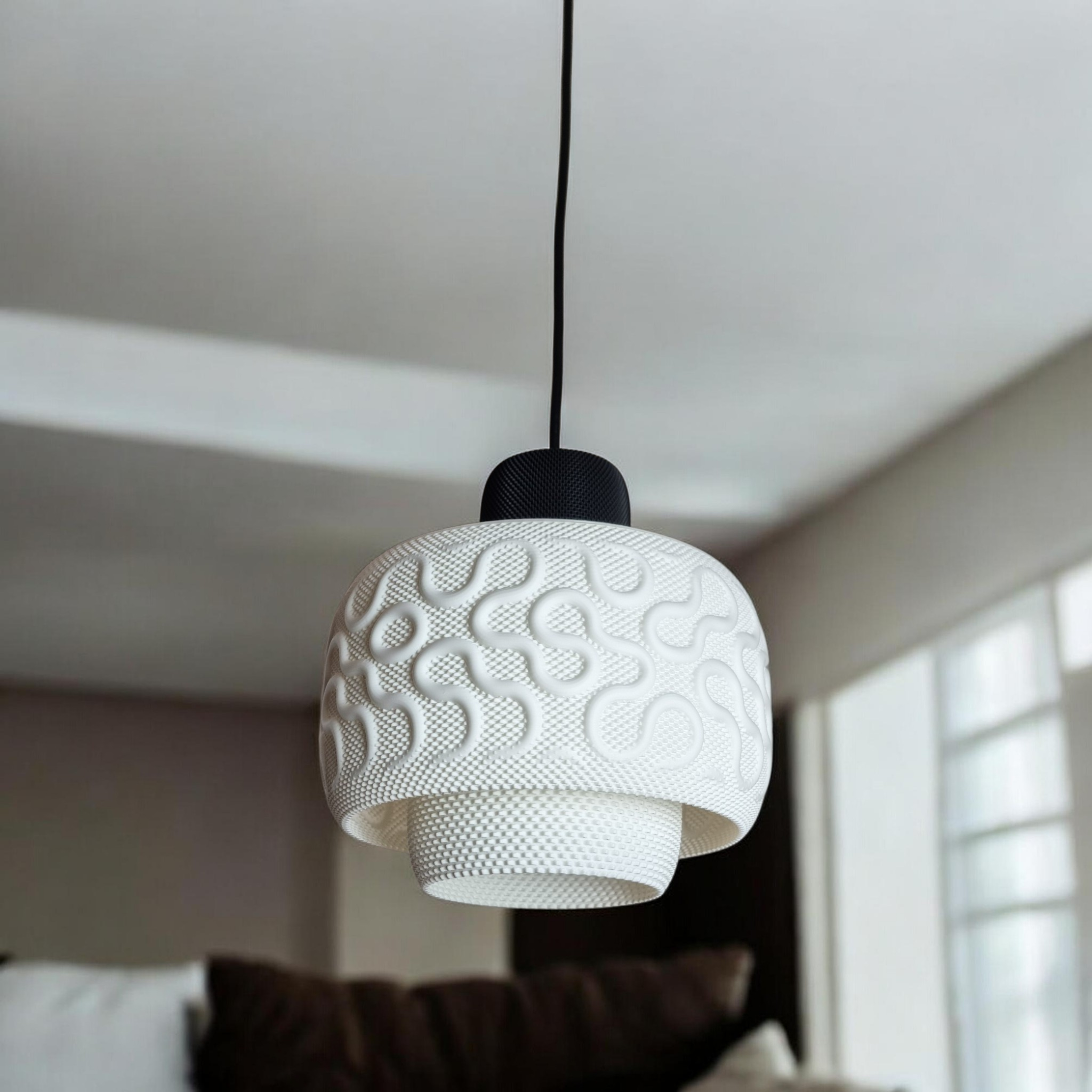 White sculptural pendant lamp SEAMLESS hanging above a sofa, close view of the organic pattern and layered drum silhouette
