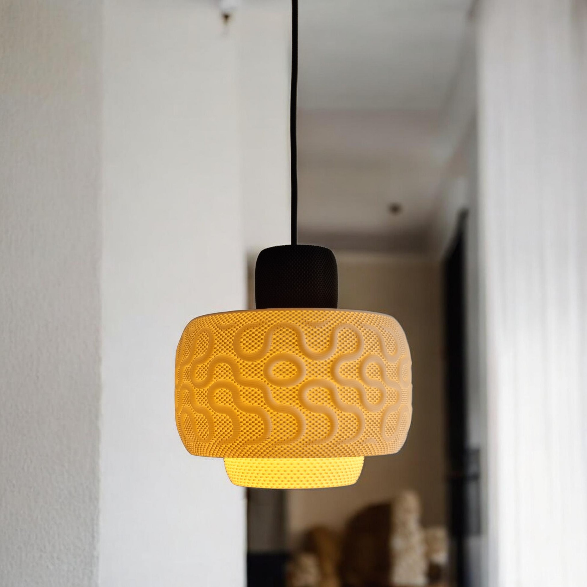 SEAMLESS pendant lamp lit in a hallway, warm glow highlighting the organic wavy pattern on the white drum shade