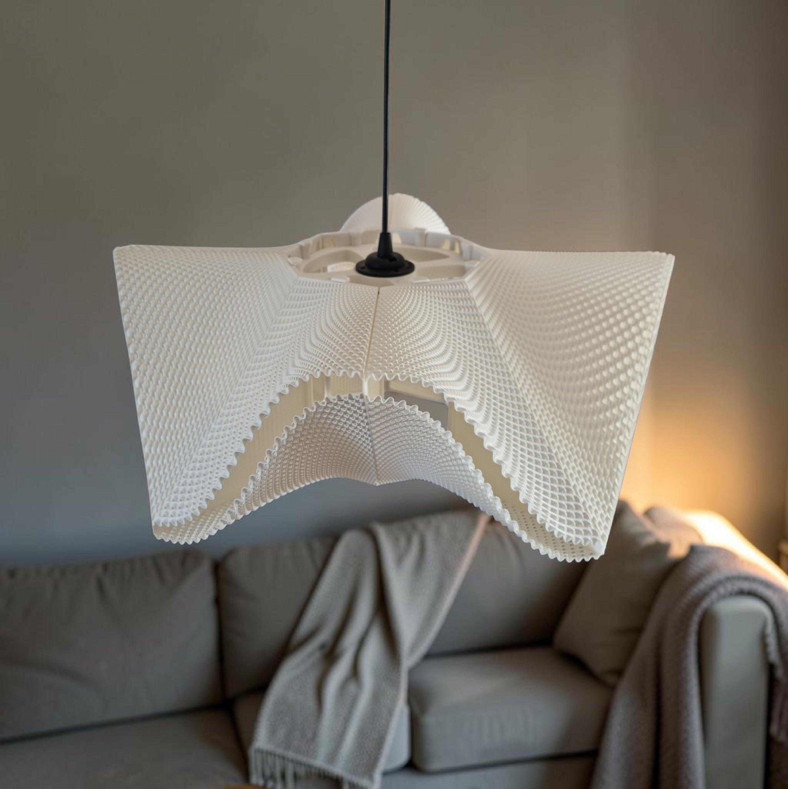 White SINE designer pendant light above a beige sofa, sculptural bioplastic lampshade for a japandi living room.