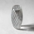 TEXTURIA Cristal vase in clear recyclable bioplastic, tilted angle with dramatic shadow, showing the full spiral silhouette and glass-effect transparency