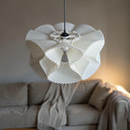 Suspension COROA en bioplastique blanc allumée au-dessus d'un canapé, abat-jour corolle texturé, luminaire impression 3D Quarks